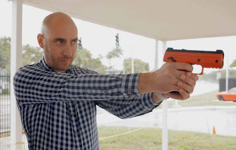 A shooter being coached through a Byrna launcher on an outdoor range