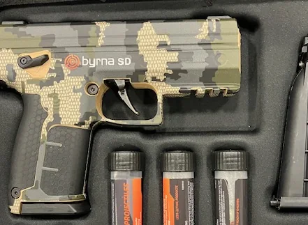 Byrna SD launcher wrapped in a green and brown digital camouflage skin with tan accents